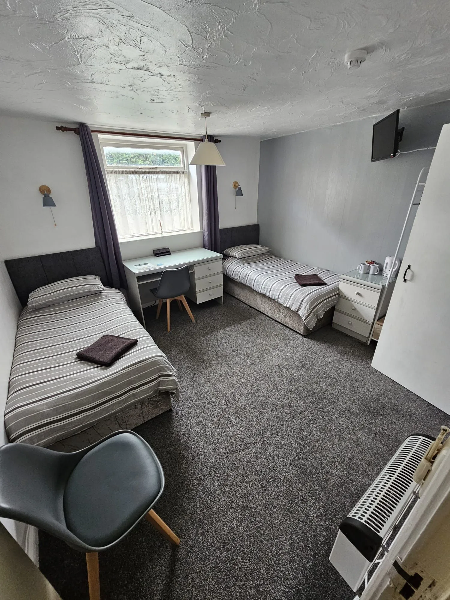 A twin room at The Coach House with two single beds, a desk and a window